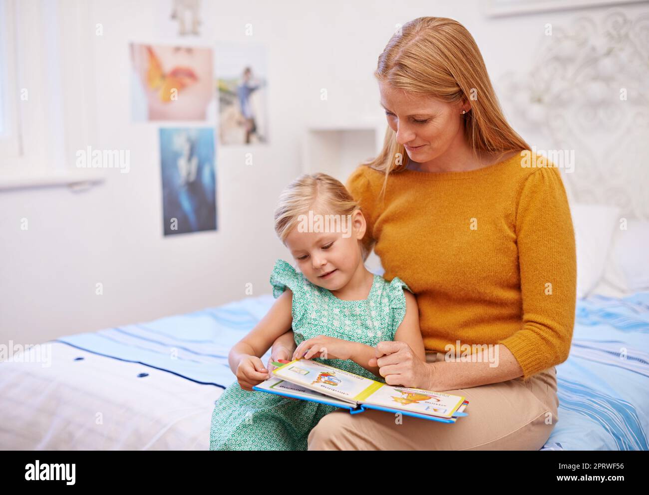 Ama le immagini, una madre che legge un libro alla bambina nella sua camera da letto. Foto Stock