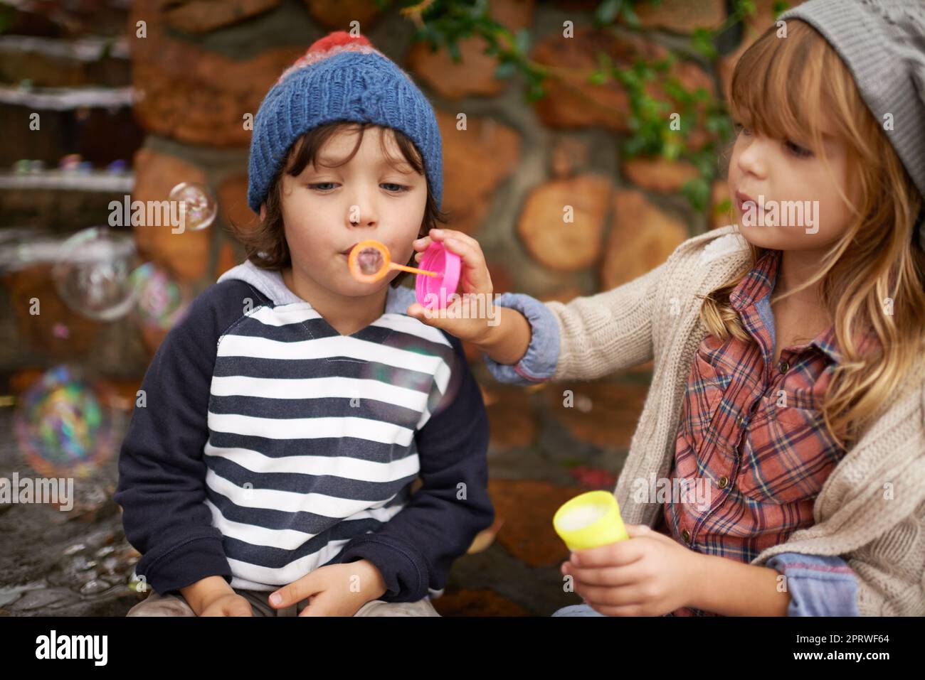 Mostrargli come è fatto. Due bambini carini che soffiano le bolle insieme all'aperto. Foto Stock