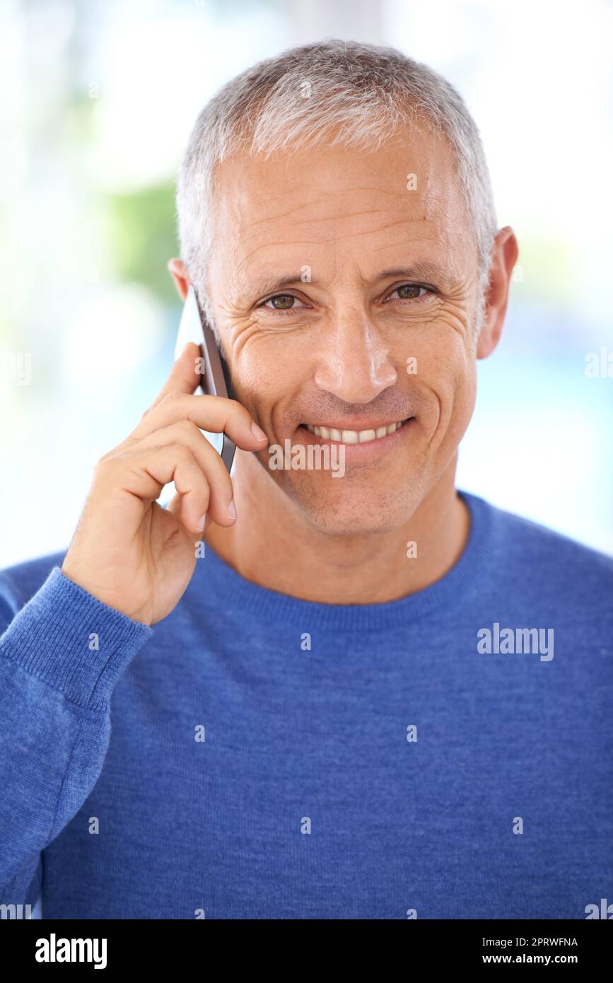 Stare al passo con le notizie di famiglia. Ritratto di un uomo maturo sorridente al telefono. Foto Stock