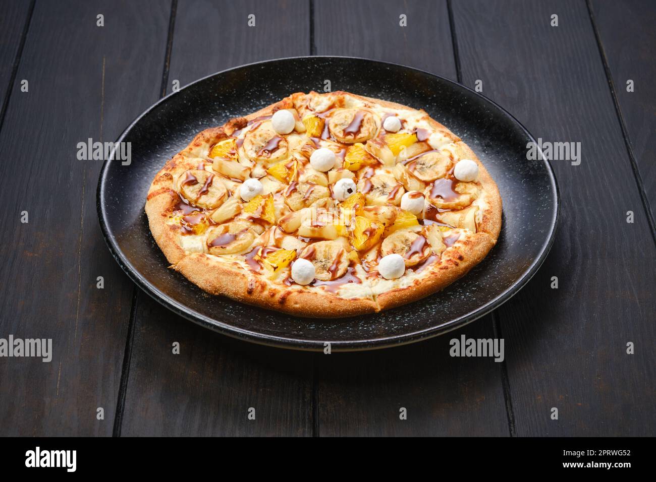 Torta dolce con banana, arancia, mirtilli rossi e sciroppo al caramello Foto Stock