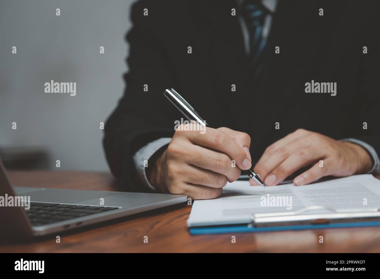 uomo d'affari che tiene il documento della firma della penna sulla clipboard alla scrivania. Informazioni commerciali avvocato di assicurazione e concetto di lavoro. Foto Stock