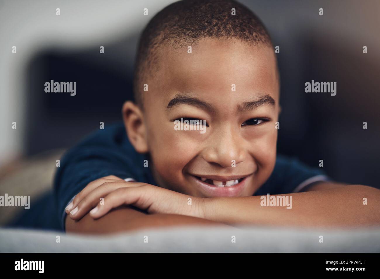 Quel sorriso dice tutto: Un adorabile ragazzino che si trova sul letto di casa. Foto Stock