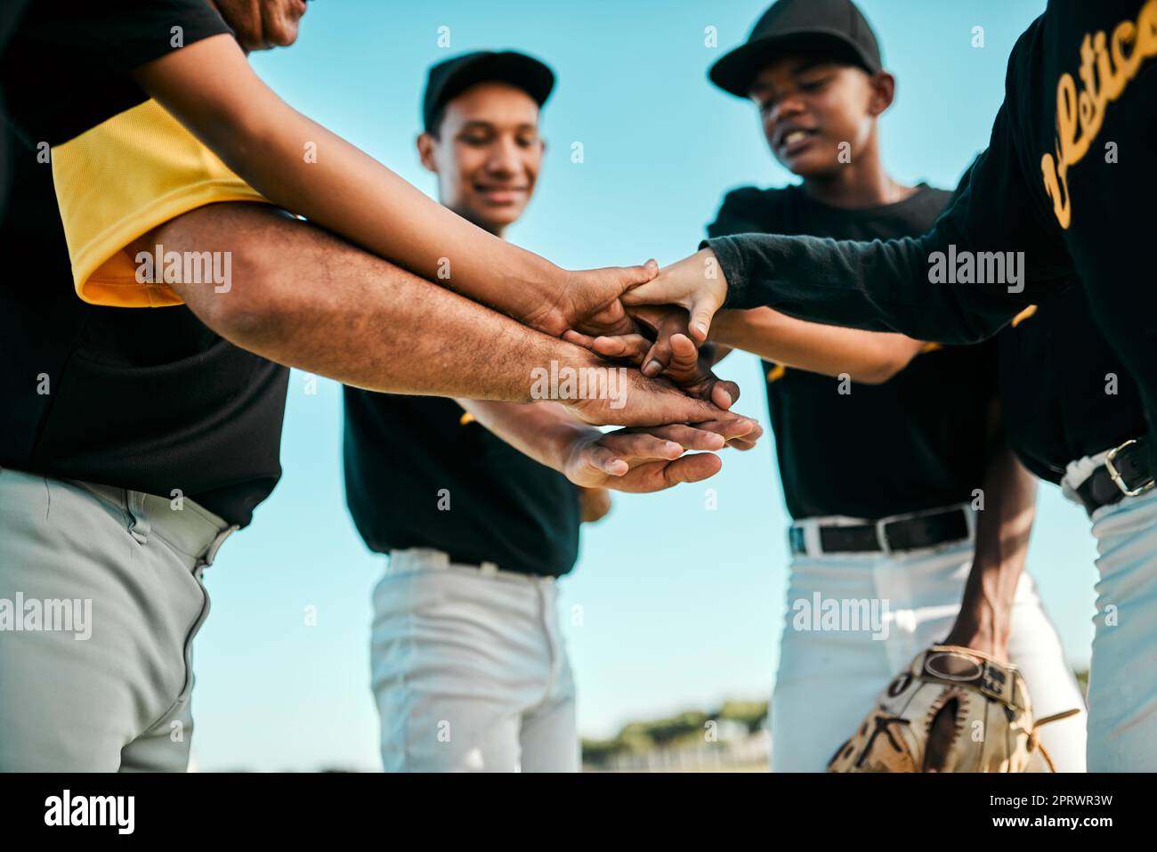 Nessun giocatore può dominare la partita. Una squadra di giovani giocatori di baseball che si uniscono le mani in un huddle durante una partita. Foto Stock