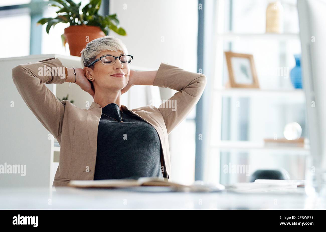 Tutto in un giorno di lavoro. Una giovane donna d'affari che fa una pausa alla sua scrivania d'ufficio. Foto Stock