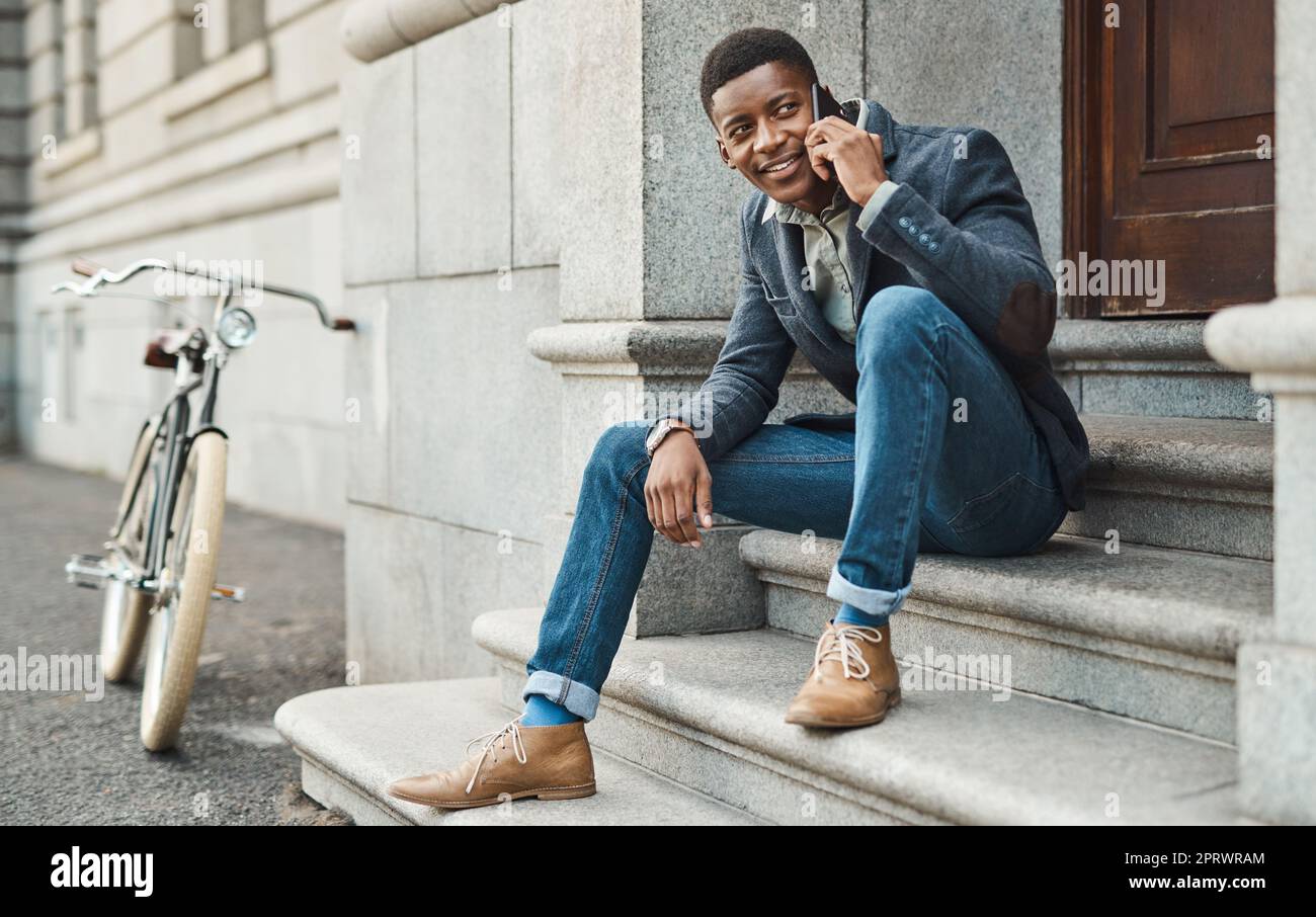 Un giovane uomo d'affari che utilizza uno smartphone in un contesto urbano rappresenta una nuova opportunità dietro ogni angolo. Foto Stock