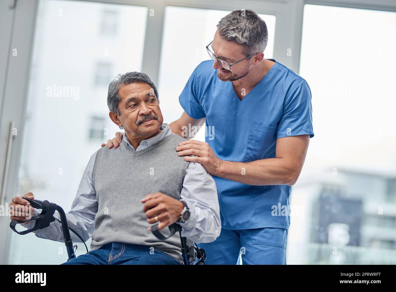 Il vostro recupero sta andando realmente bene. Un'infermiera che aiuta un anziano con un camminatore. Foto Stock