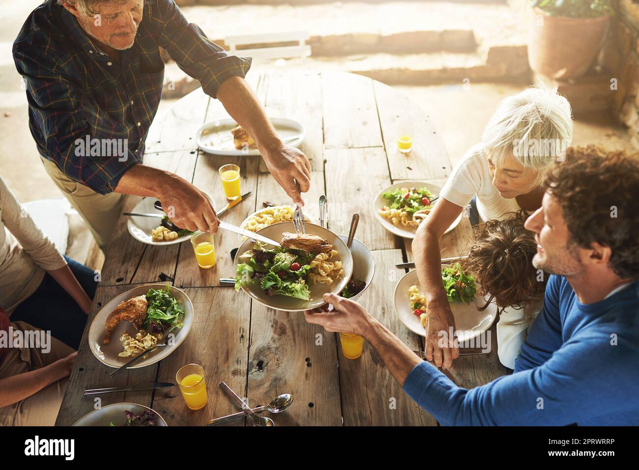 Cmon tutti, piatto su. Inquadratura ad alta angolazione di una famiglia per pranzare insieme all'aperto. Foto Stock