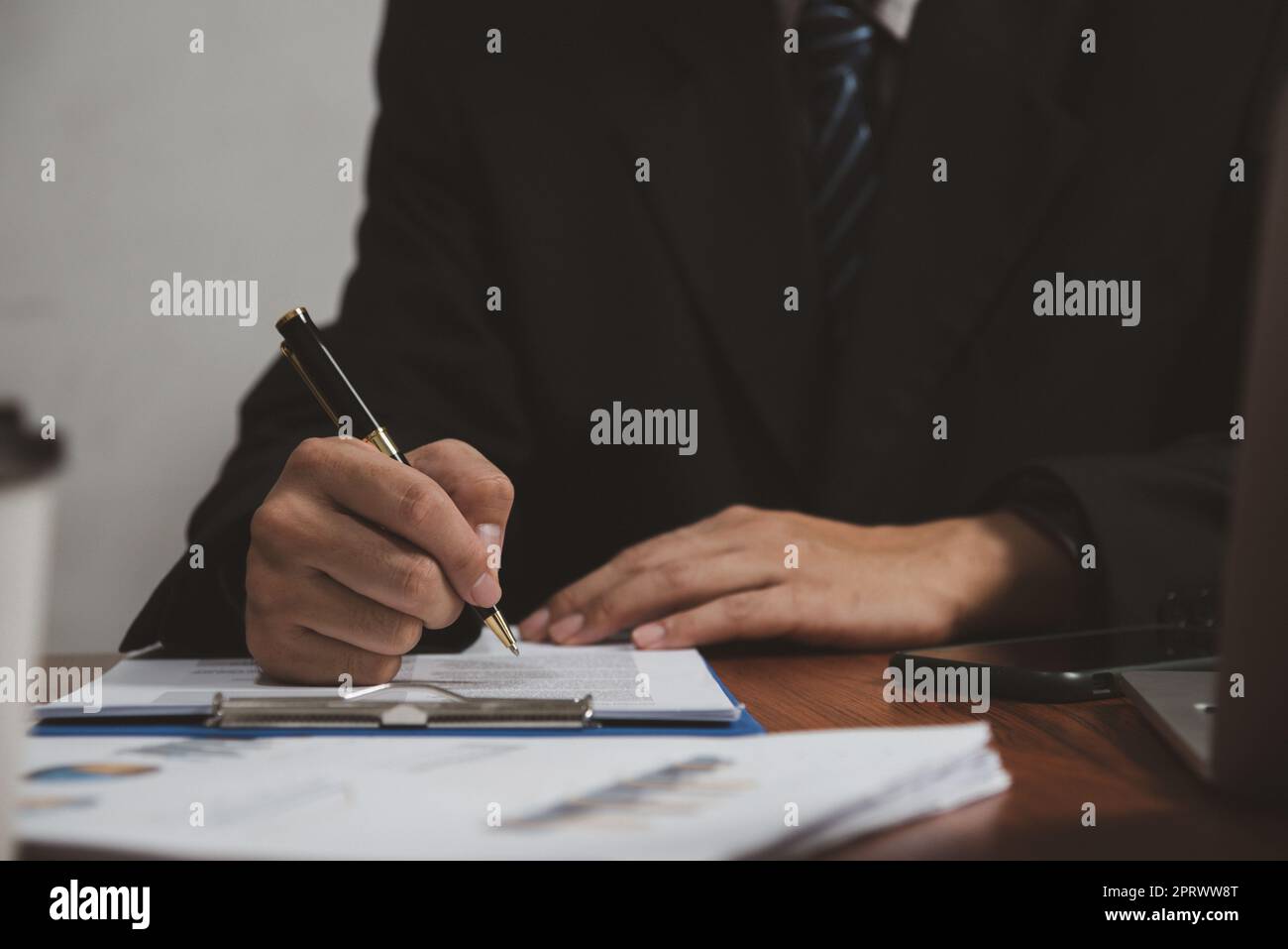 uomo d'affari che tiene il documento della firma della penna sulla clipboard alla scrivania. Informazioni commerciali avvocato di assicurazione e concetto di lavoro. Foto Stock