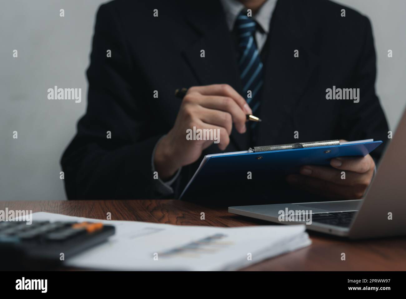 uomo d'affari che tiene il documento della firma della penna sulla clipboard alla scrivania. Informazioni commerciali avvocato di assicurazione e concetto di lavoro. Foto Stock