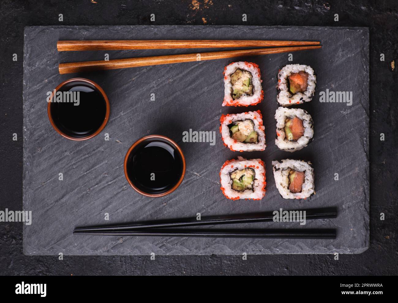 Involtini di sushi giapponesi su piatto di pietra nera Foto Stock