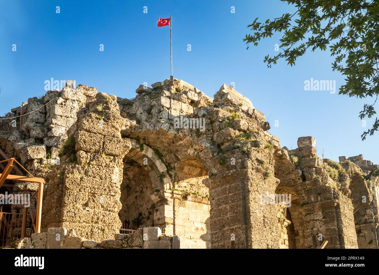La bandiera turca rossa vola in cima alle principali rovine dell'anfiteatro vicino al Tempio di Dioniso a lato dell'antica città romana in Turchia (Turkiye). Th Foto Stock