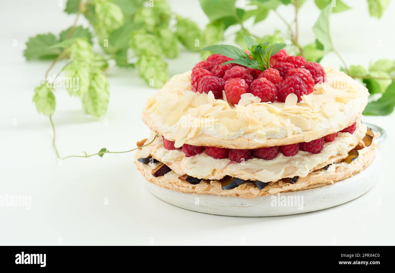 Torta di meringa rotonda con lamponi freschi su sfondo bianco, Pavlova dessert Foto Stock