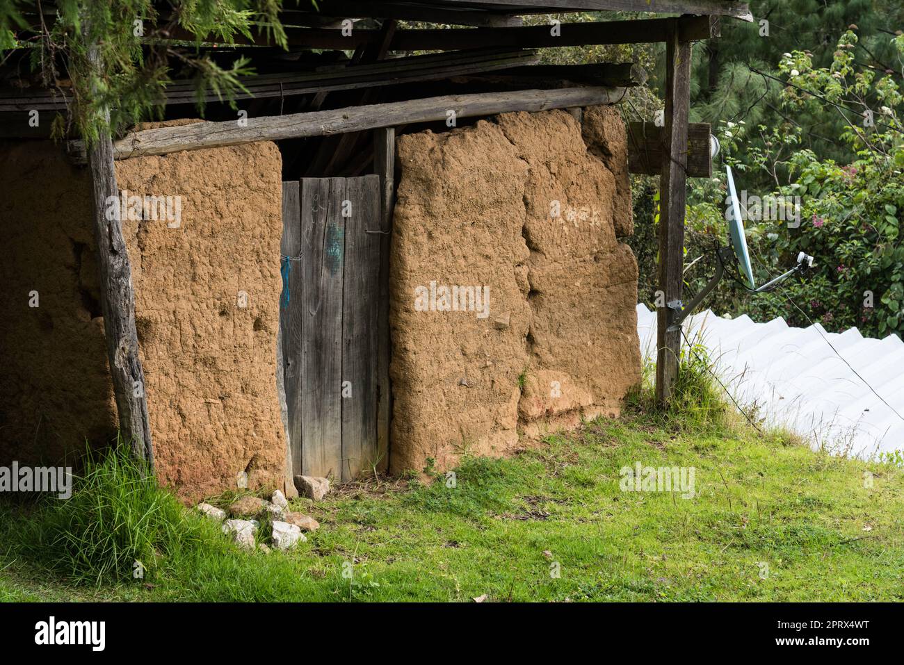 Studio in contrasti. Un piatto satellite su un vecchio edificio tradizionale in mattoni di adobe nella Sierra Madre del sur Mountains, Oaxaca, Messico. Foto Stock