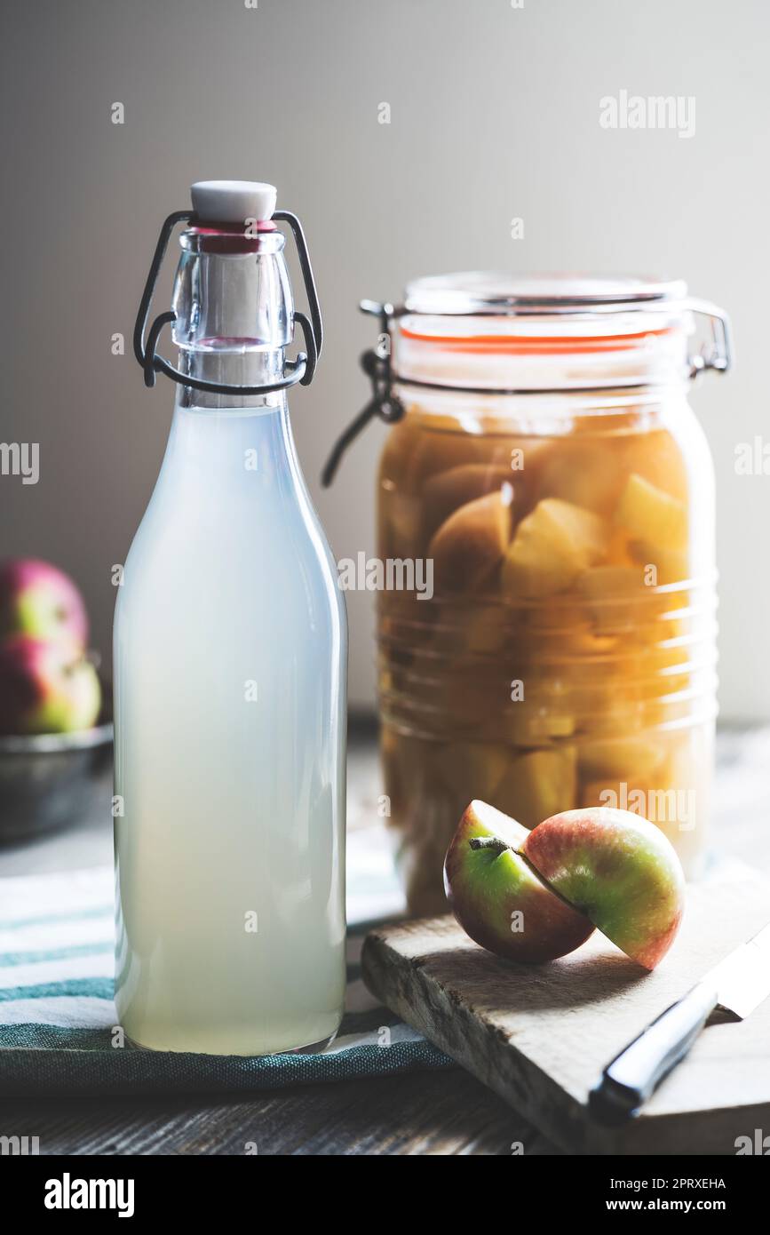 Bottiglia di aceto di sidro di mela su sfondo rustico Foto Stock