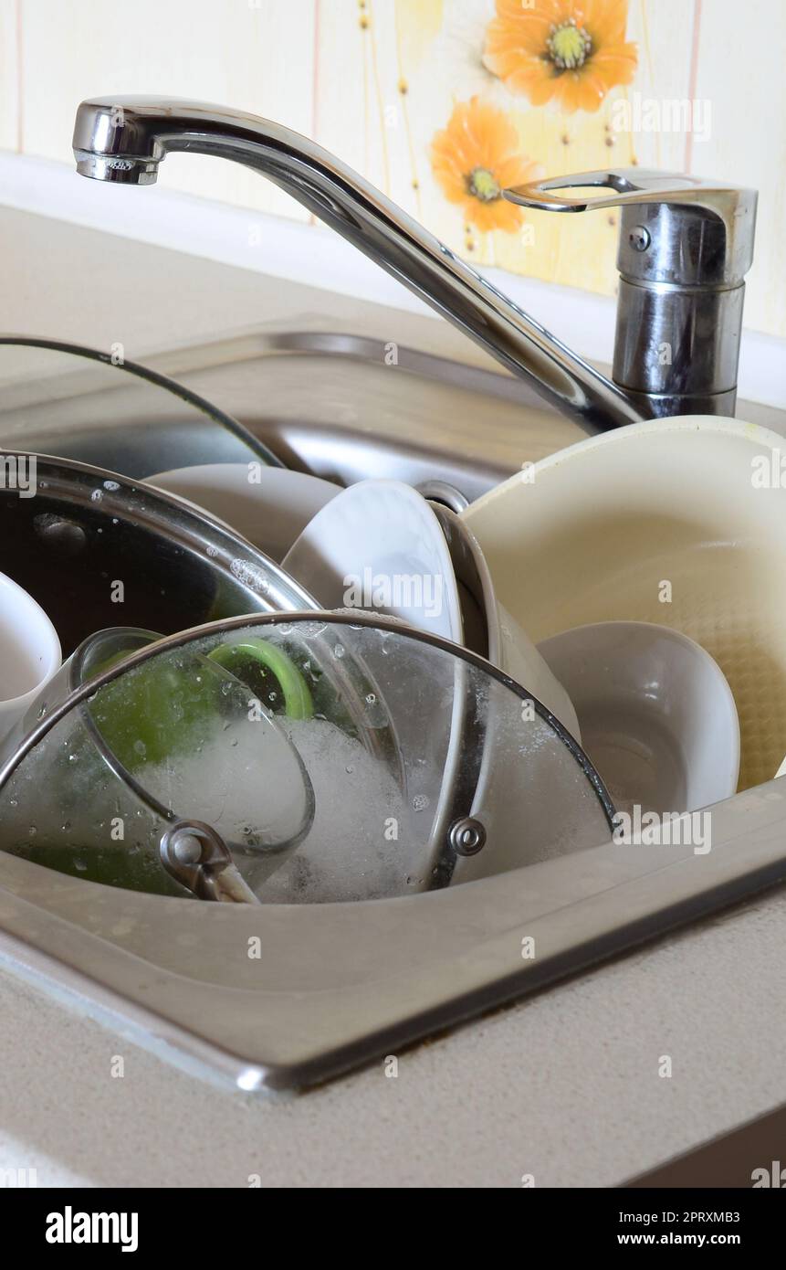 I piatti sporchi e gli elettrodomestici da cucina non lavati riempivano il lavandino della cucina Foto Stock