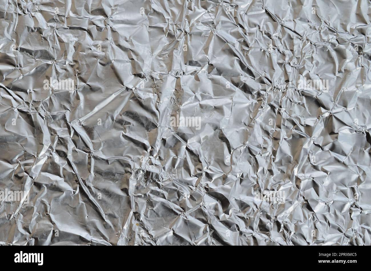 Sottile foglio stropicciato di alluminio stagnato argento sfondo con superficie lucida stropicciata per la texture Foto Stock