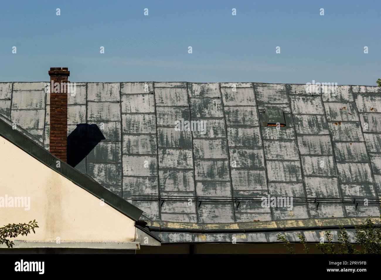 Tetto in metallo di una casa indipendente e camino contro il cielo, tegole in metallo, grondaie. Foto Stock
