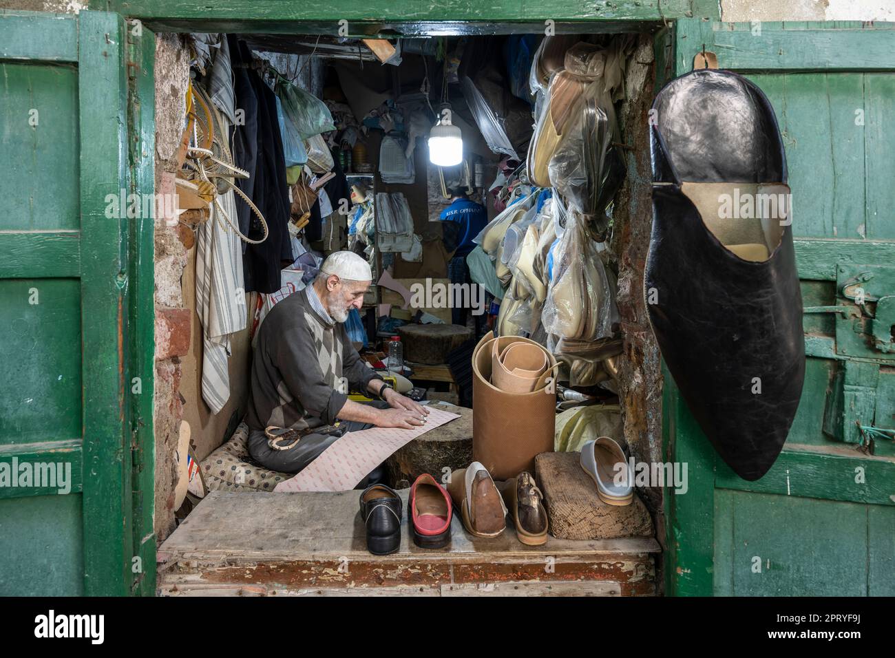 Calzolaio artigiano che taglia sottopiedi in pelle per la fabbricazione di pantofole. Foto Stock