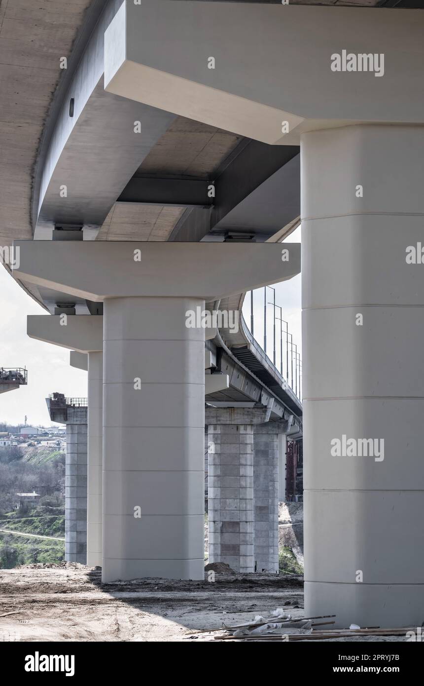 Pilastro del ponte. Lato inferiore di una strada sopraelevata. I pilastri grigi sostengono il peso della struttura. Parte vitale dell'infrastruttura. Scarica l'immagine Foto Stock