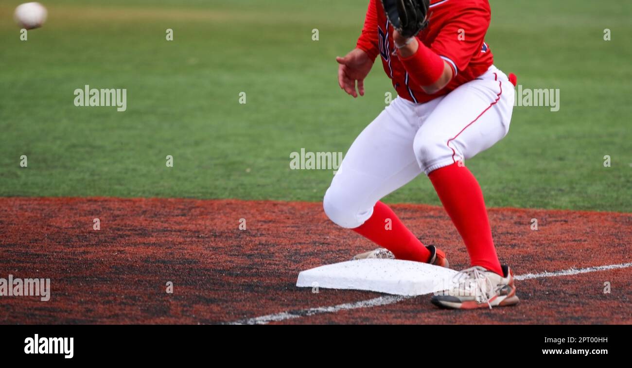 Palla gettata dall'outfed al terzo baseman per taggare fuori il corridore durante una partita di baseball della High School. Foto Stock