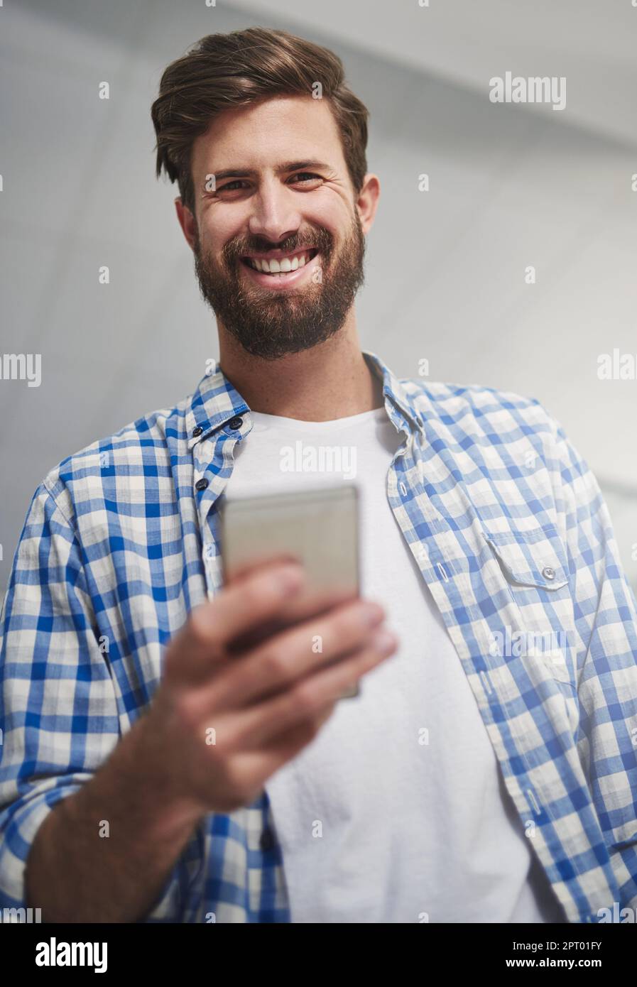 Non riesco a immaginare di fare affari senza tecnologia. Ritratto di un giovane designer utilizzando un cellulare in un ufficio moderno Foto Stock