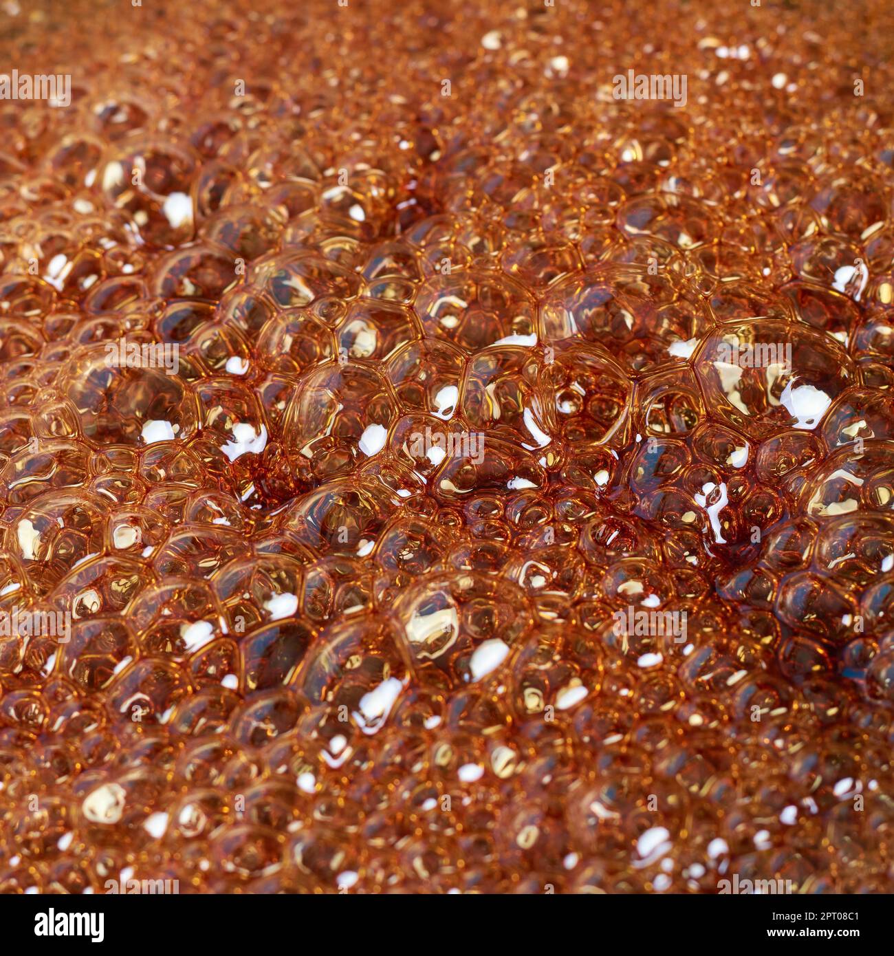 primo piano delle bolle quando lo zucchero bollente si trasforma in caramello, astratto in pieno sfondo della caramellizzazione, fuoco selettivo Foto Stock