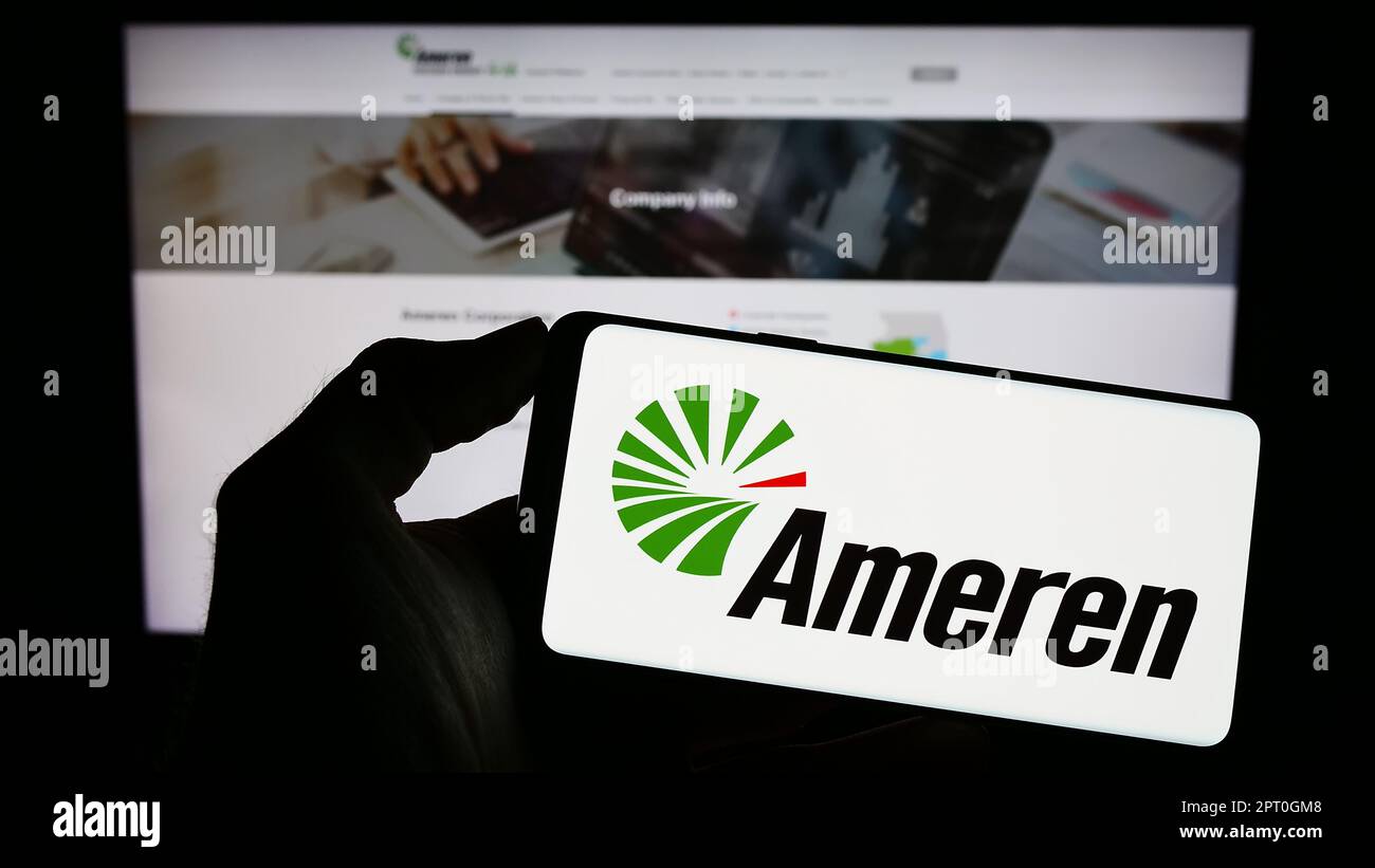 Persona che tiene uno smartphone con il logo della società americana di energia Ameren Corporation sullo schermo di fronte al sito Web. Messa a fuoco sul display del telefono. Foto Stock