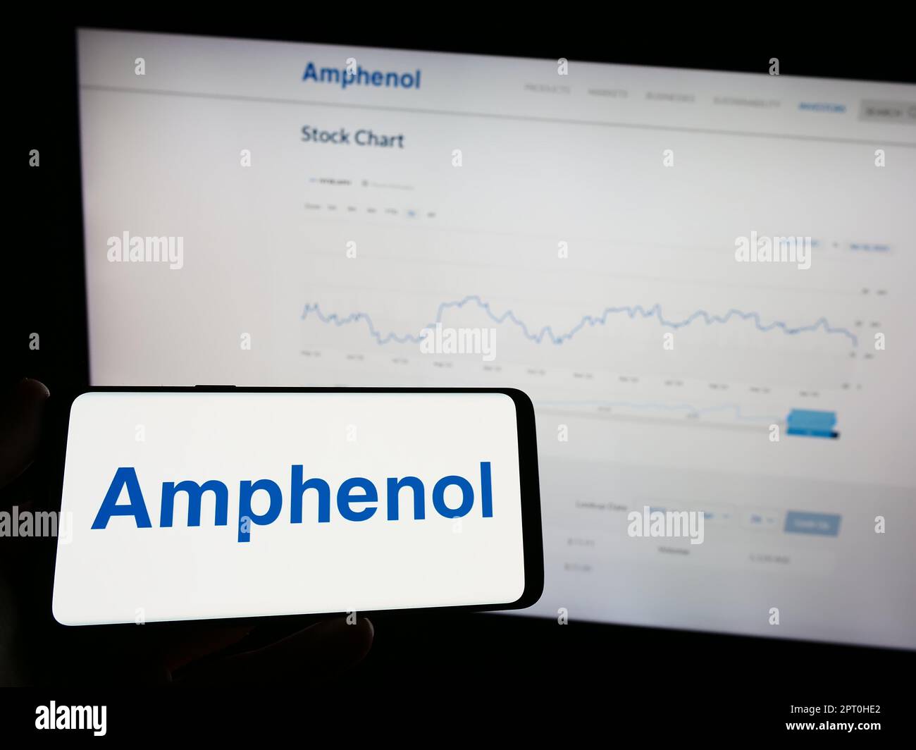 Persona che tiene il telefono cellulare con il logo della società americana di elettronica Amphenol Corporation sullo schermo di fronte alla pagina web. Messa a fuoco sul display del telefono. Foto Stock
