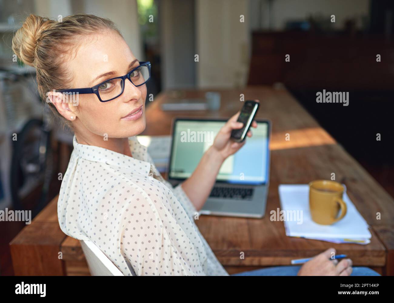 Il lavoro autonomo è la strada da percorrere. Una giovane donna che usa il cellulare mentre lavora da casa Foto Stock