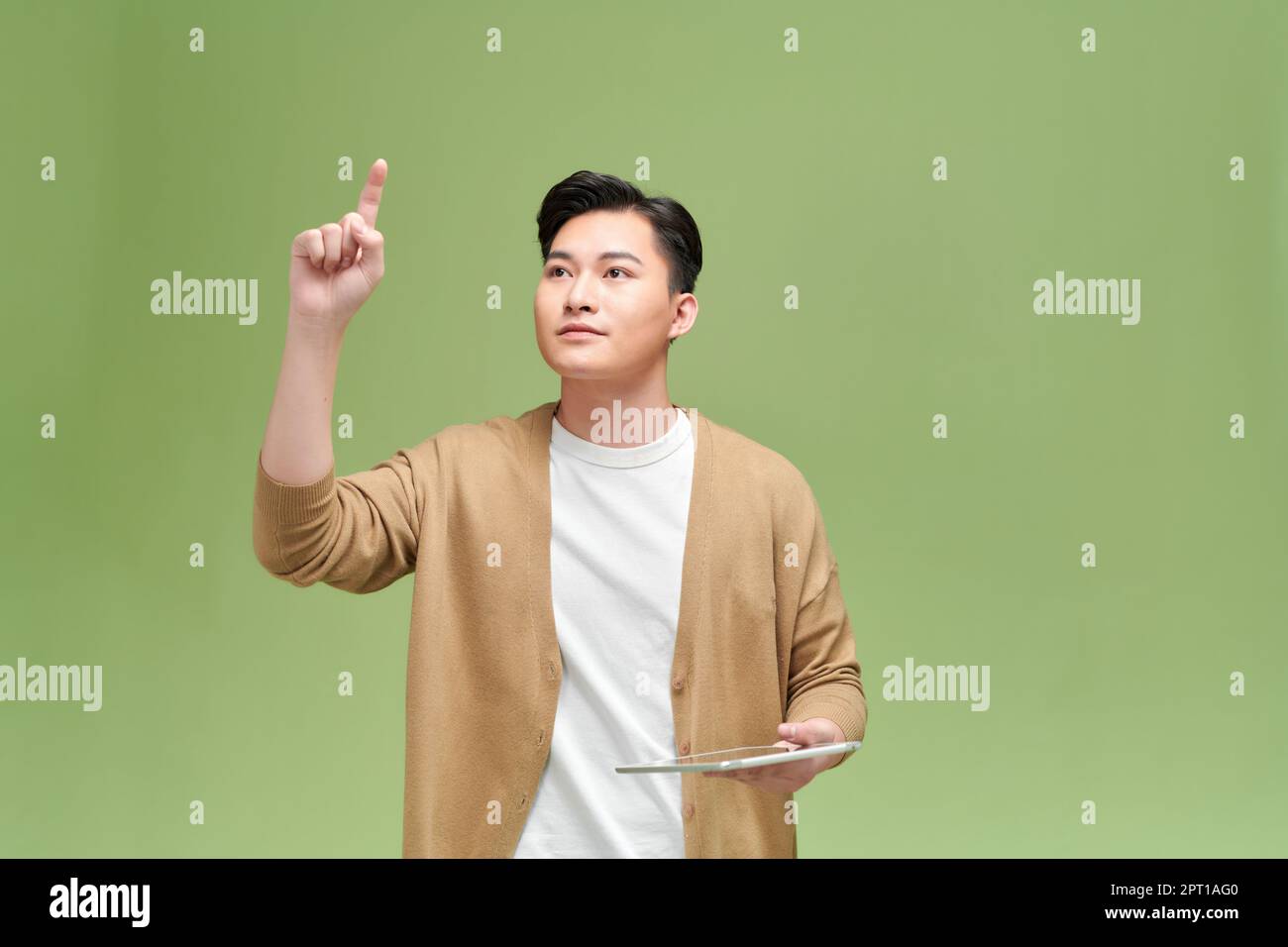 Ritratto di un uomo asiatico eccitato tiene la tavoletta in mano, alza la mano, punta all'aria Foto Stock