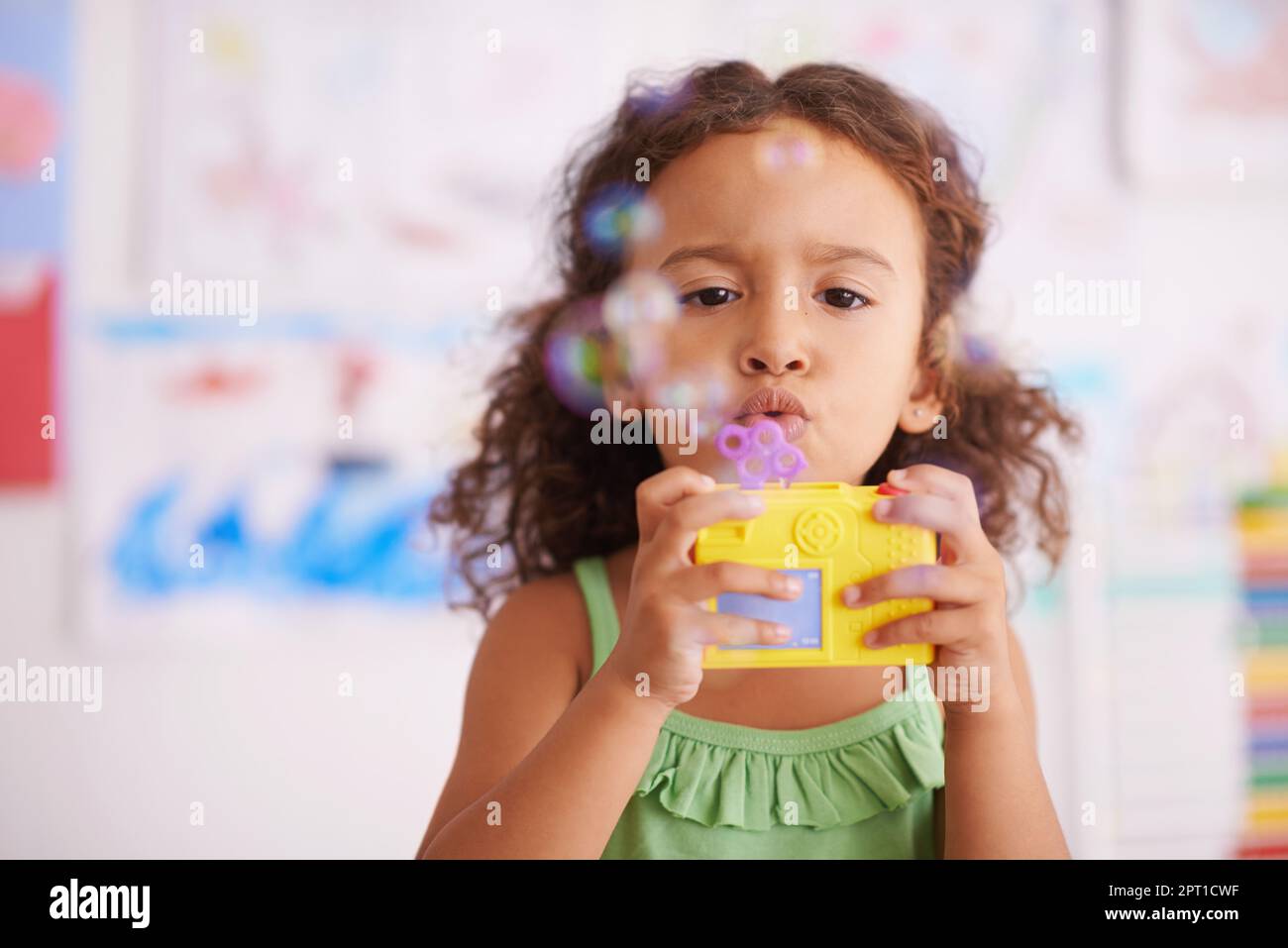 Bubblicious divertimento. Una bambina adorabile che soffia bolle nella sua camera da letto Foto Stock