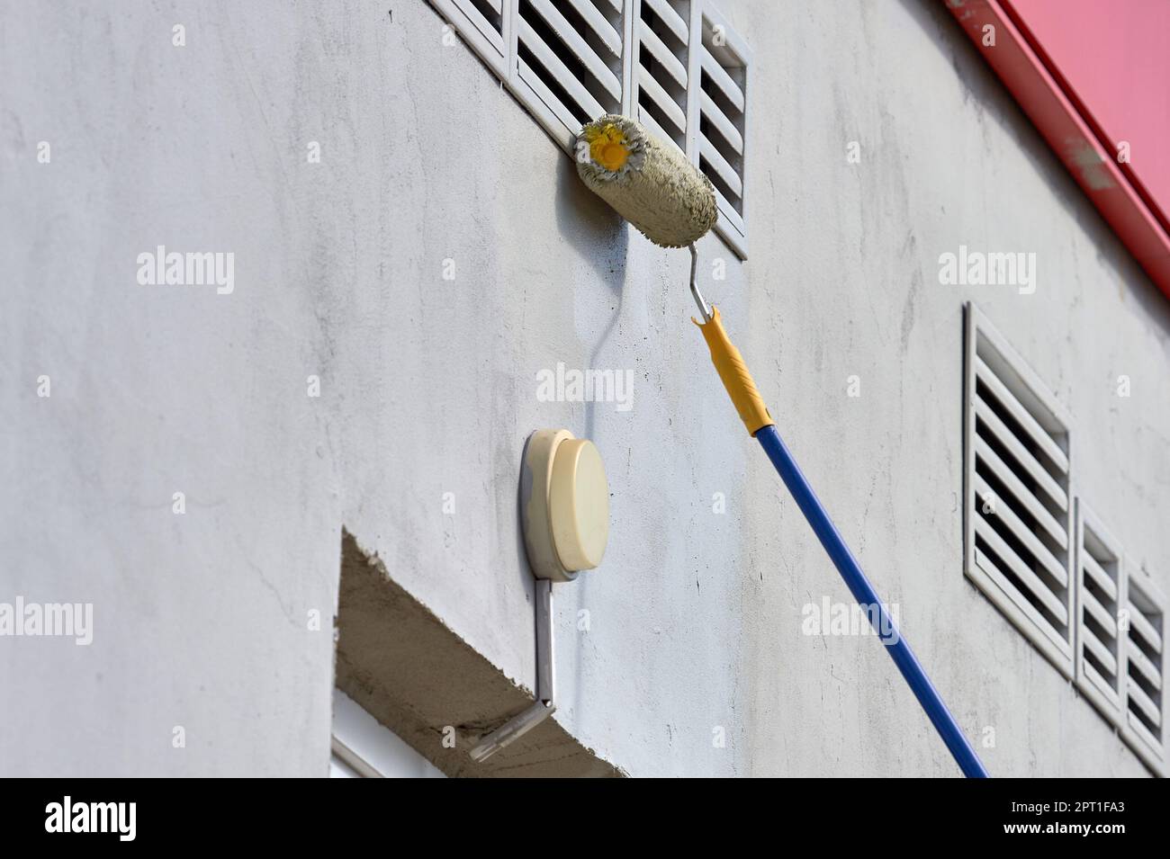 dipingere il muro della strada con un rullo di vernice grigia. Foto di alta qualità Foto Stock