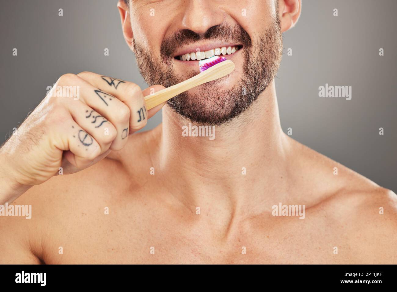 Uomo, bocca e spazzolino per la cura dentale, igiene e salute con una spazzola su uno sfondo grigio studio. Igiene orale, denti sani e wellbei dentale Foto Stock