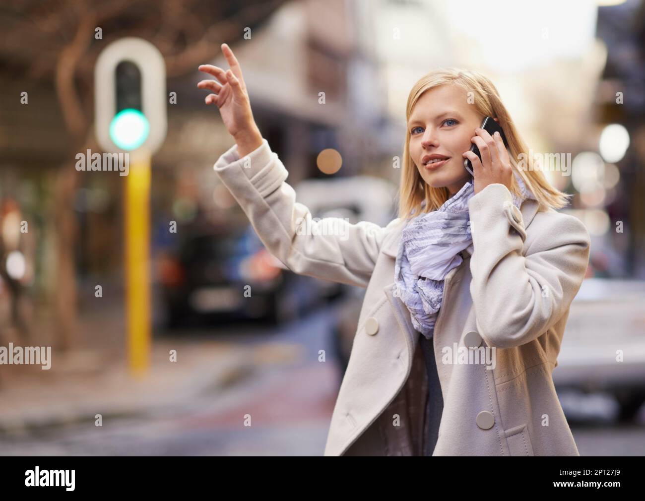 Aspetta, im prendere un taxi. una giovane donna che salutava un taxi mentre parlava sul suo cellulare Foto Stock