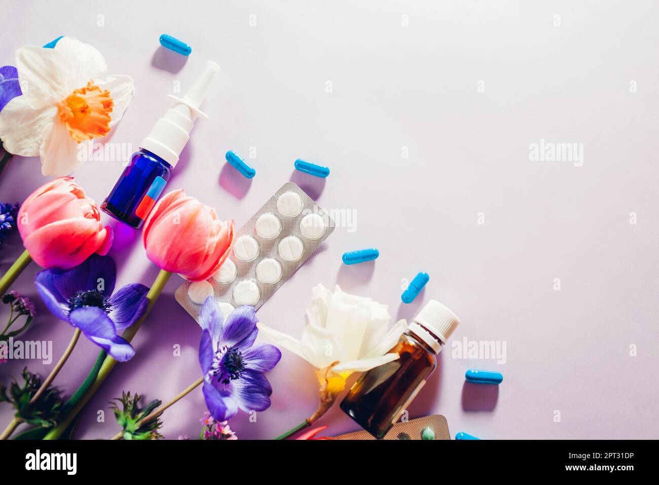 Allergia primaverile stagionale. Pillole e spray nasale piatto steso con fiori rosa viola. Trattamento allergico ai pollini. Vista dall'alto. Spazio Foto Stock