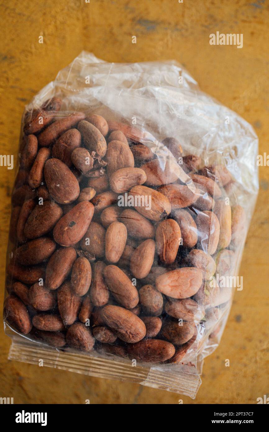 Sacchetto di plastica trasparente di cacao messicano, cacao in grani su fondo dorato Foto Stock