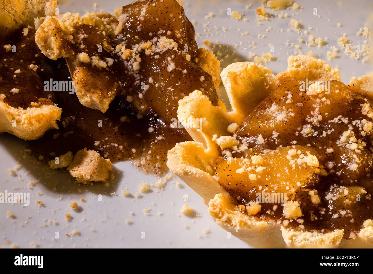 100mm Macro di tartine di mele, crostate piccole, torta piccola, briciole, crosta di pasta frolla e spezzata a pezzi. Foto Stock