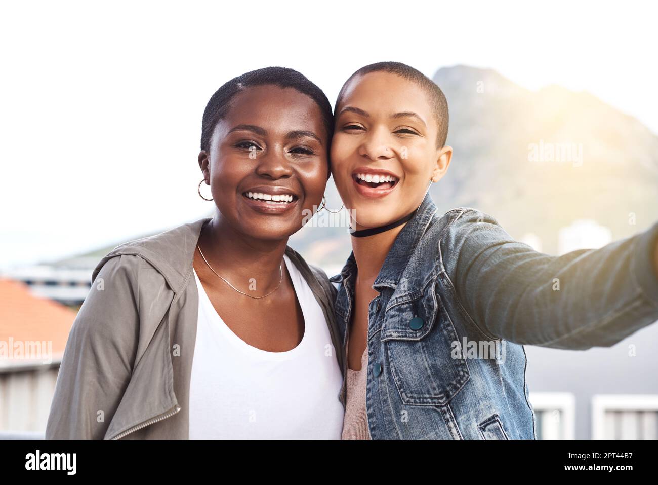 Riunita finalmente. Ritratto di due giovani donne sorridenti e in posa mentre scattano un selfie in città Foto Stock