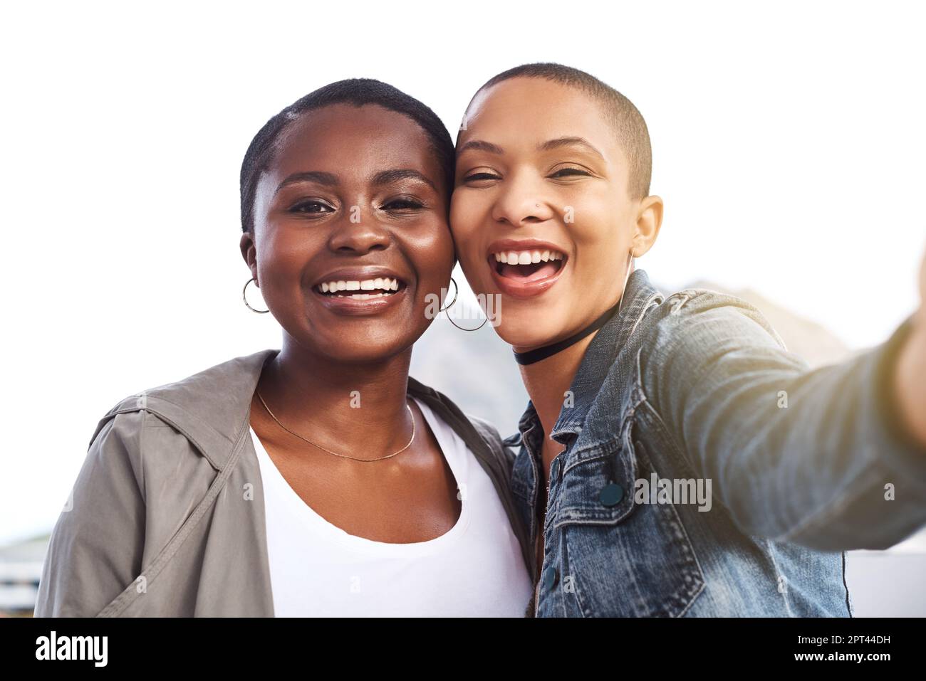 Lo yin al mio yang. Ritratto di due giovani donne sorridenti e in posa mentre scattano un selfie in città Foto Stock