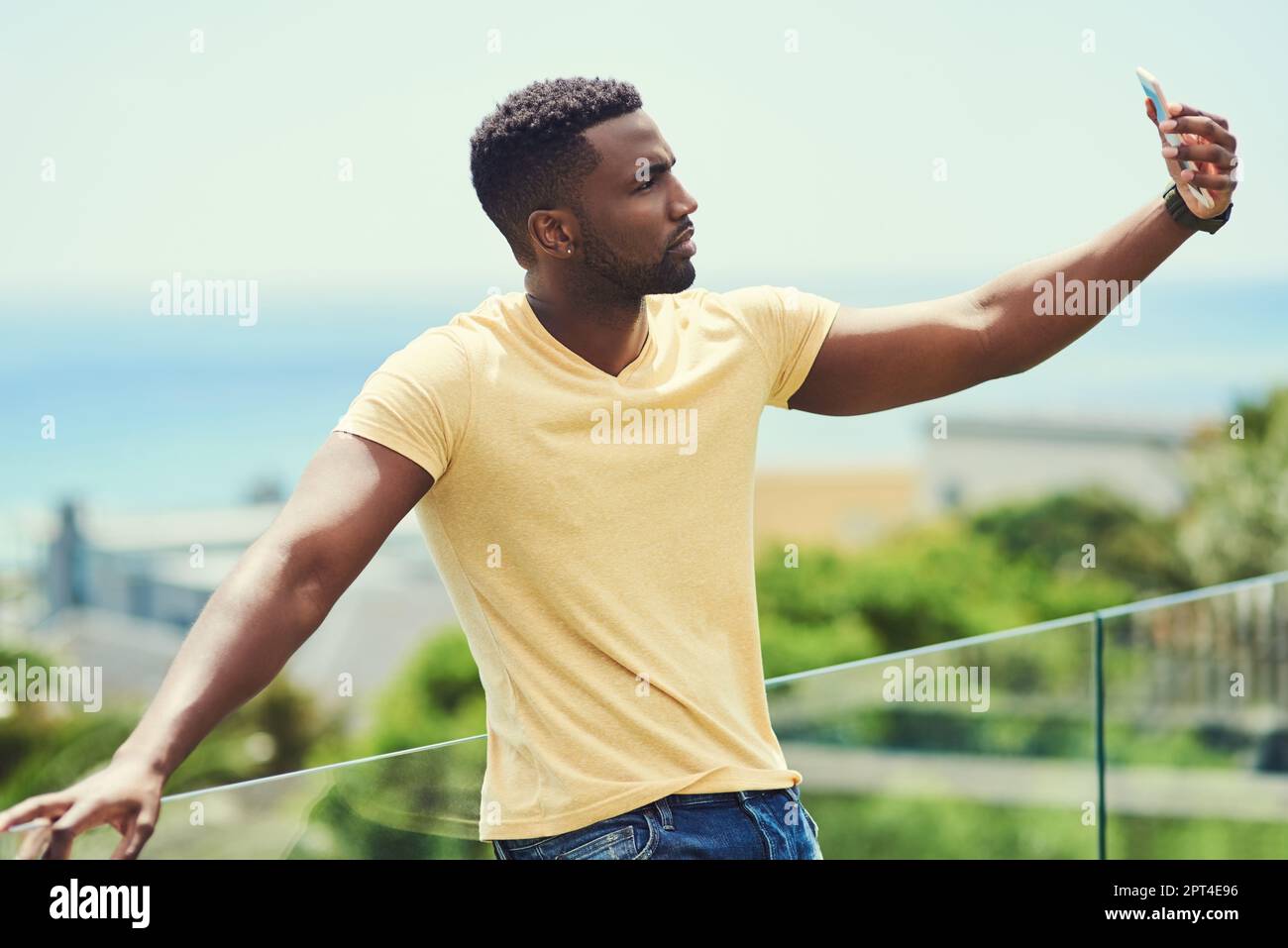 Scenario perfetto, selfie perfetto. un bel giovane uomo che prende un selfie con il suo cellulare mentre si rilassa all'aperto in vacanza Foto Stock