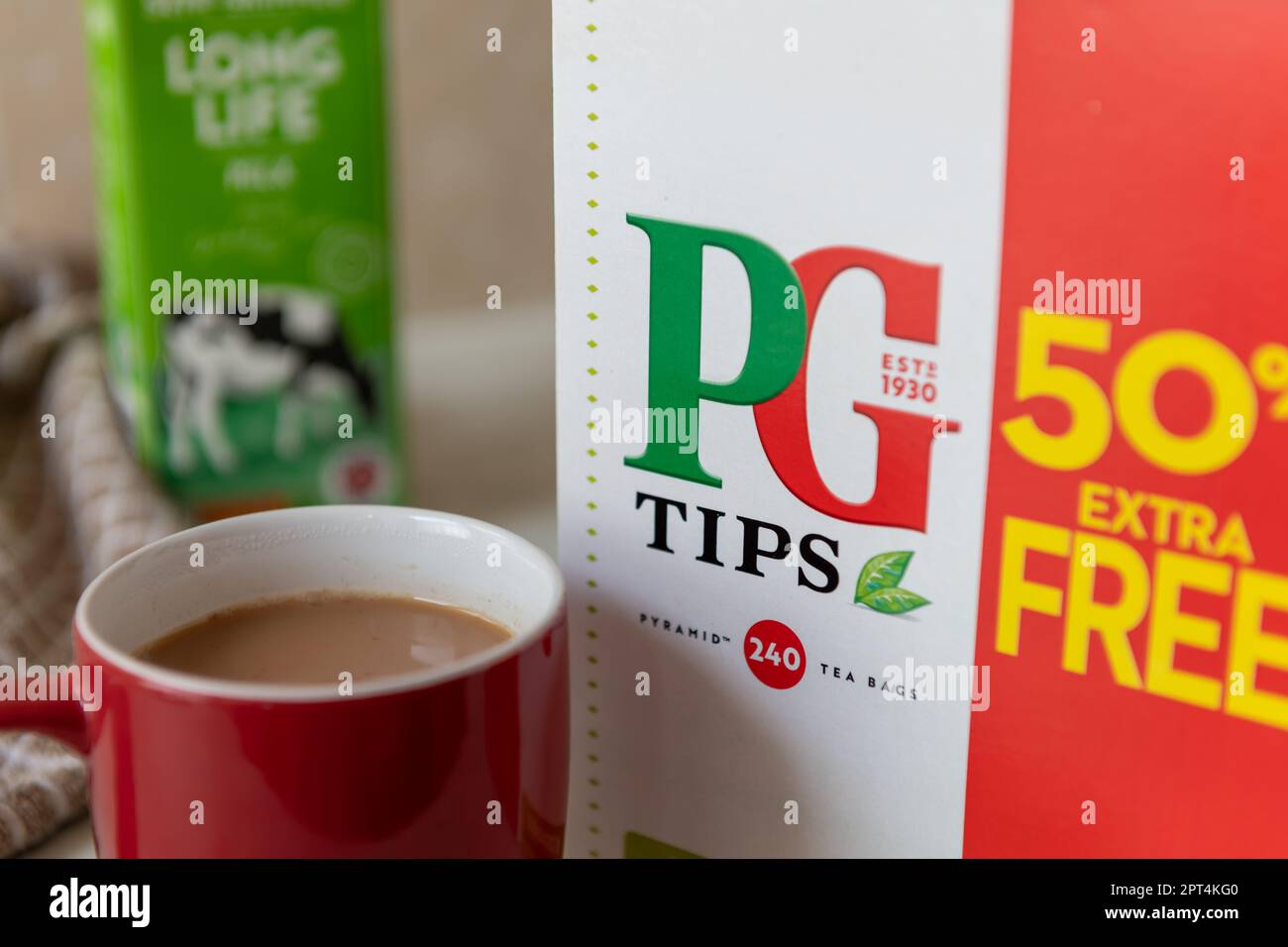 Londra. UK- 04.19.2023. Primo piano di una grande scatola di PG Tips bustine di tè con una tazza di tè al latte e latte sullo sfondo. Foto Stock