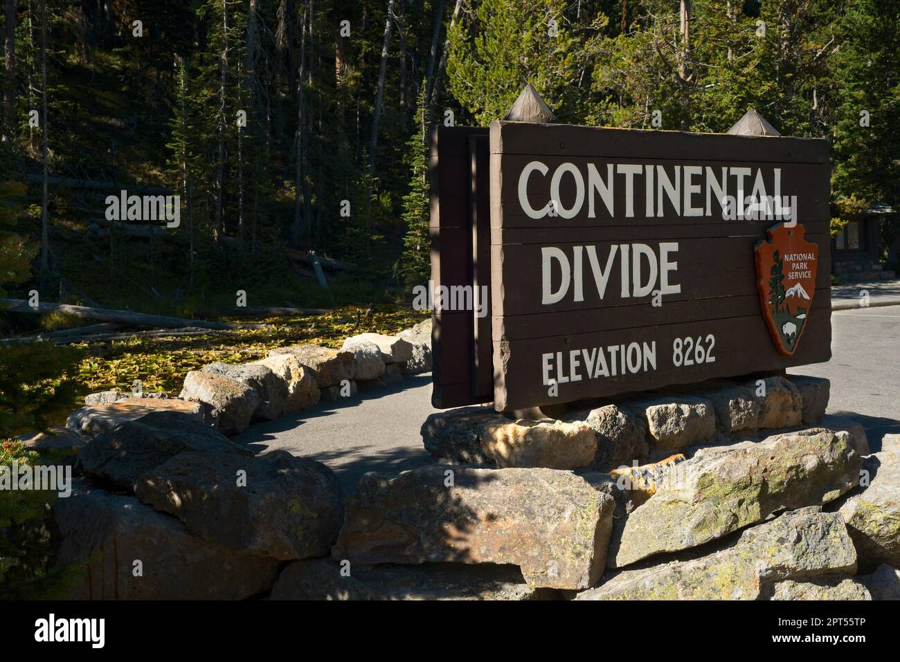 Il Continental divide al Passo di Craig nel Parco Nazionale di Yellowstone, con il lago Isa coperto da giglio dietro il cartello Foto Stock