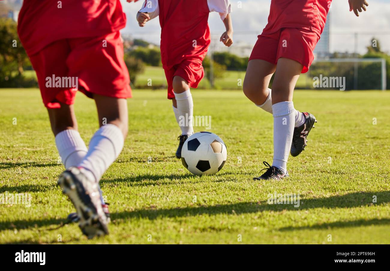 Squadra di bambini, calcio o gambe con pallone da calcio in allenamento, gioco di fitness o esercizio sul prato del parco naturale, stadio di scuola superiore o campo. Calcio o sport Foto Stock