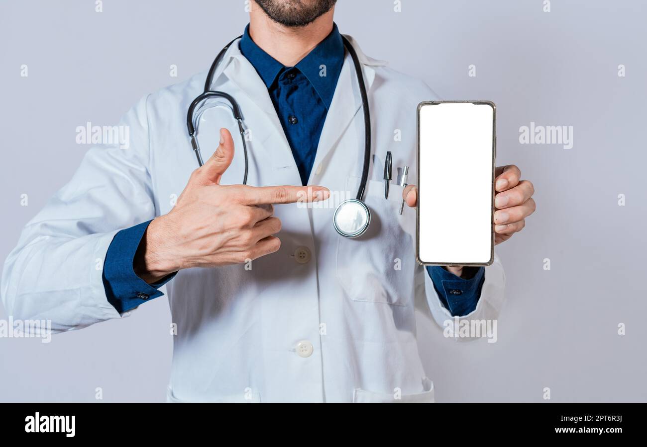 Il medico mostra e indica lo schermo del telefono cellulare vuoto. Medico che consiglia sullo schermo del telefono cellulare isolato Foto Stock
