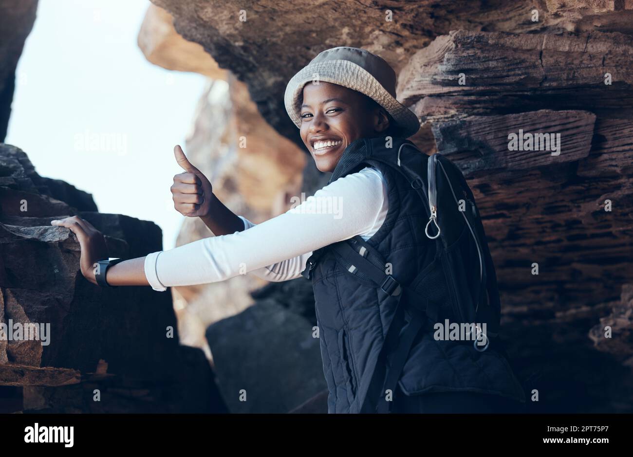Donna, pollici su e successo escursionistico in montagna grotta, ambiente di campagna o paesaggio remoto Namibia. Ritratto, sorriso e motivazione fitness hik Foto Stock