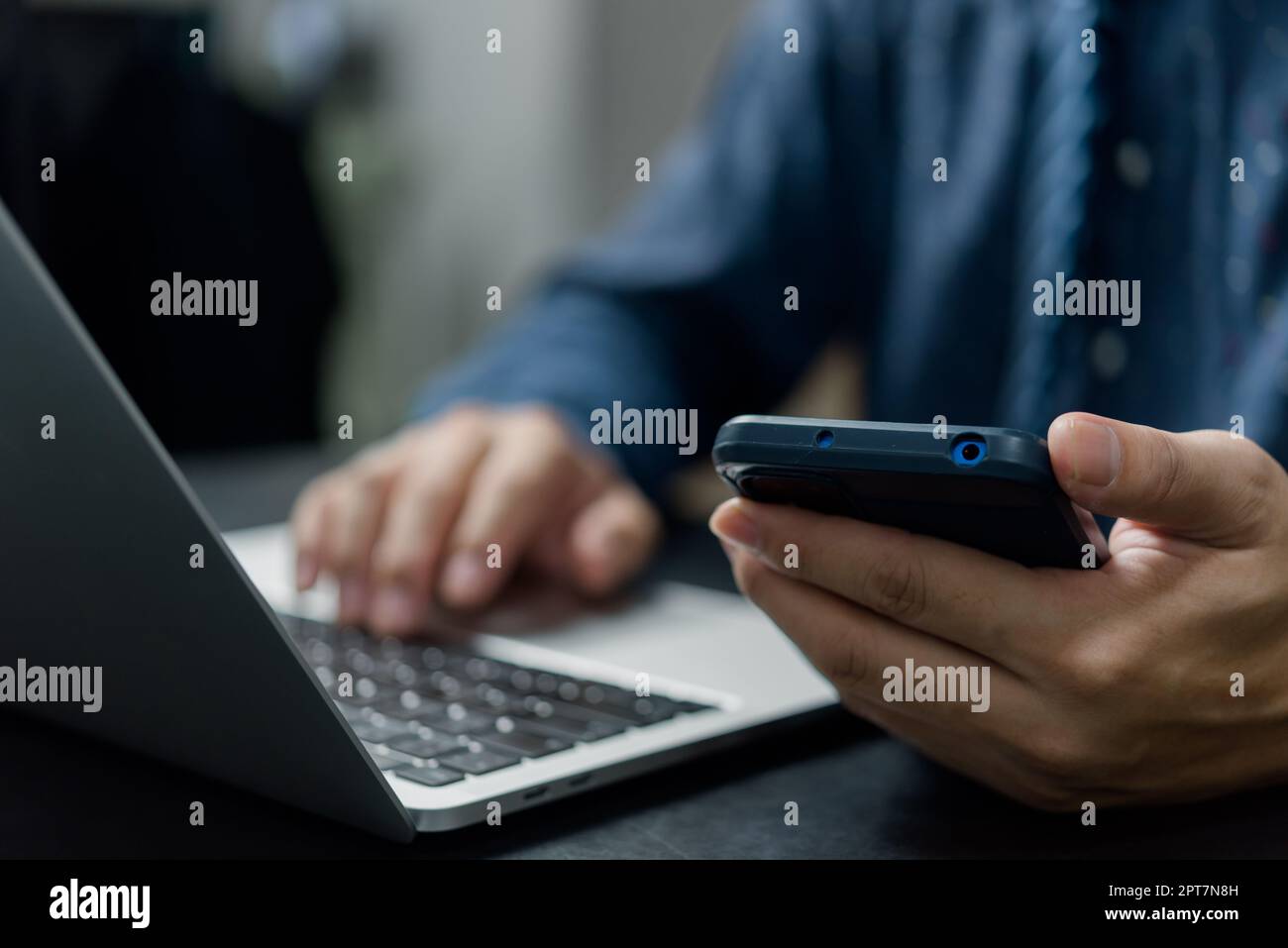 Uomo che tiene le comunicazioni di rete con tecnologia digitale per smartphone alla scrivania. Foto Stock