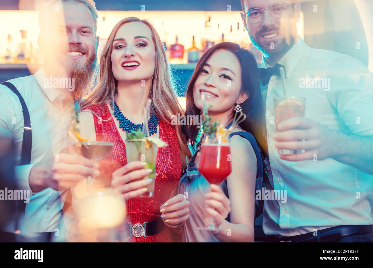 Gruppo di amici diversi con cocktail al bar sorridendo e guardando la macchina fotografica Foto Stock
