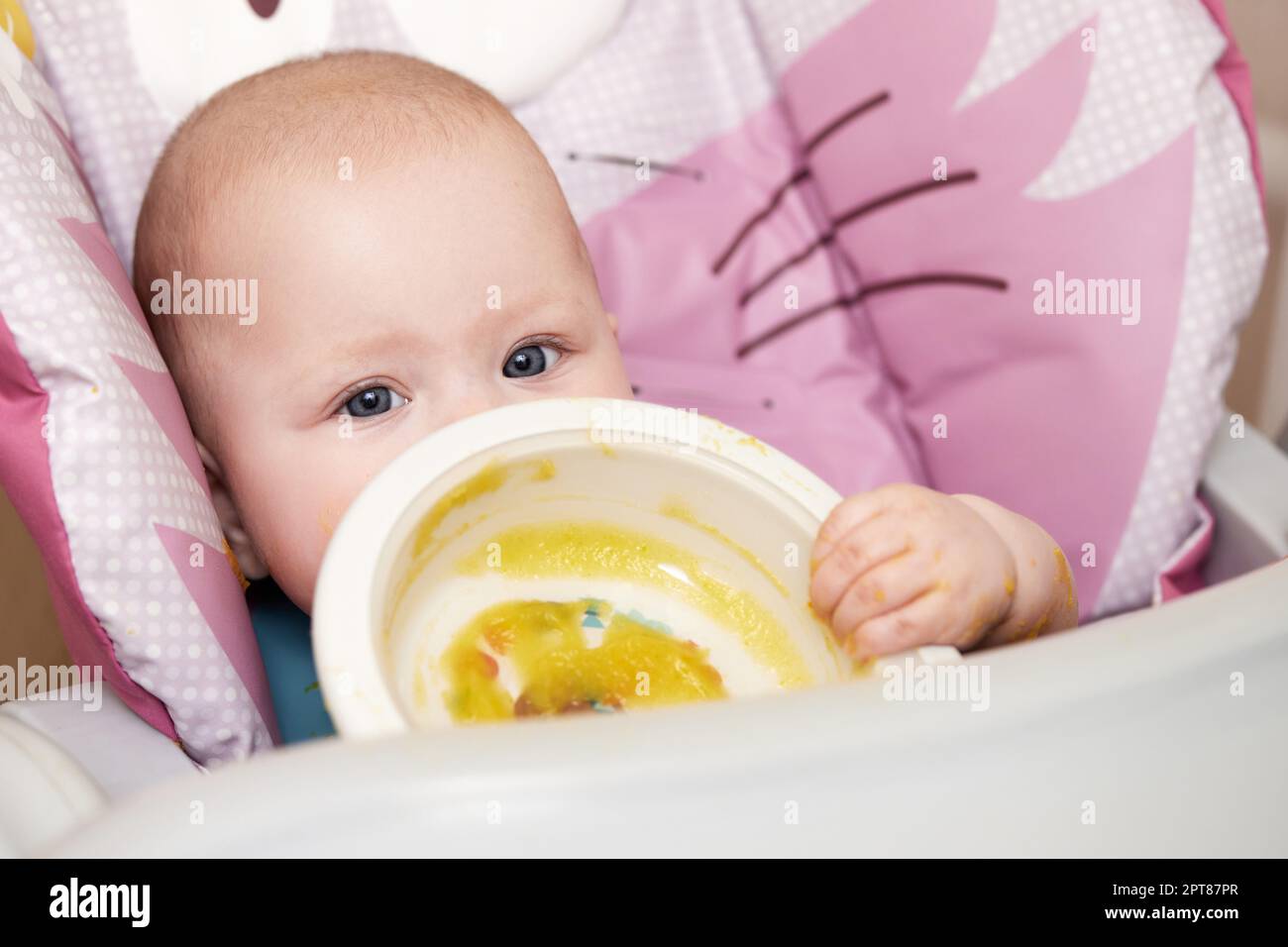 ragazza cute del bambino ha mangiato le verdure schiacciate sulla sedia del bambino Foto Stock