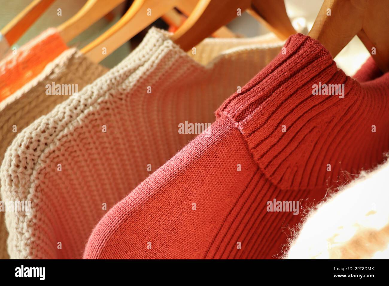 Pullover caldi su un appendiabiti da guardaroba su uno sfondo chiaro. Autunno, abiti invernali. Foto Stock