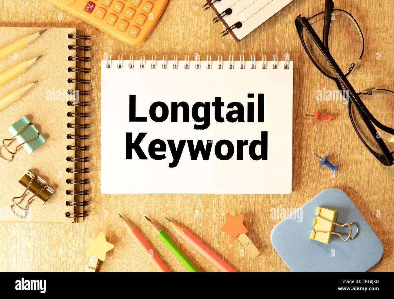 Pezzo di carta bianco con testo parola chiave lunga sullo sfondo dei grafici, penne multicolore con punta in feltro. Foto Stock